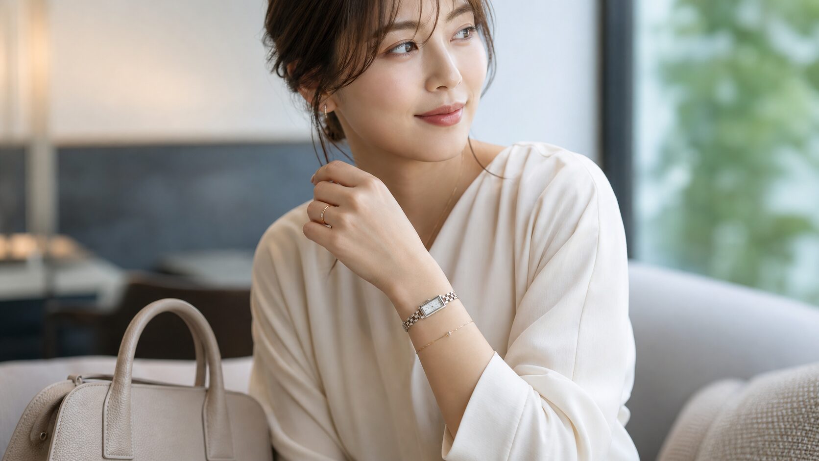 ブレスレットのような華奢な腕時計とアクセサリーを着けた日本人女性